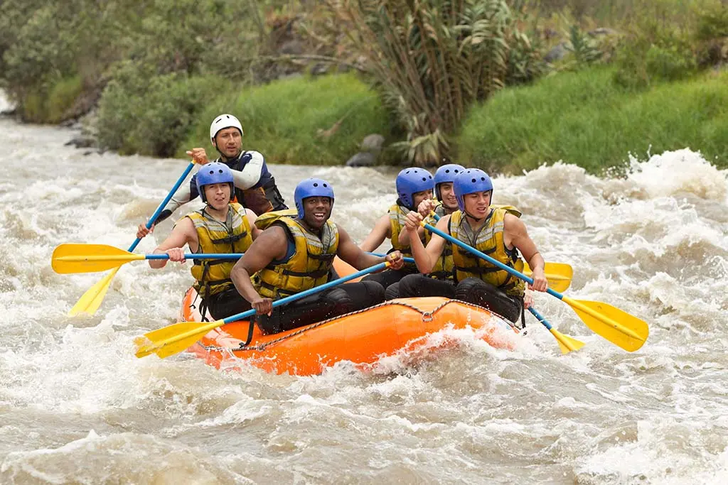 Group of rafters navigating white-water rapids on a sunny day